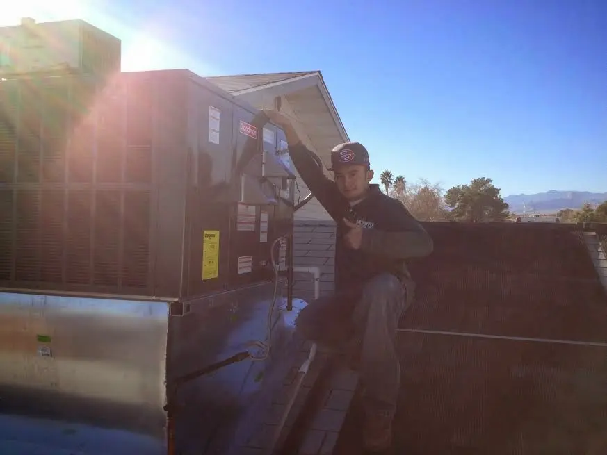 HVAC technician performing AC Tune-Up on a rooftop unit in Fletcher