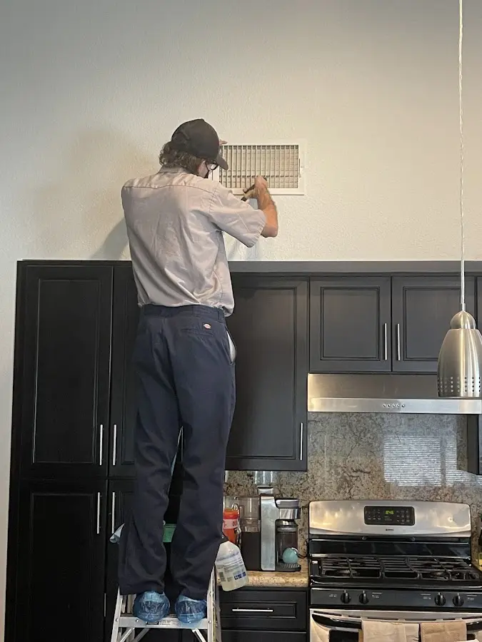 Technician inspecting an air vent during HVAC service in Fletcher
